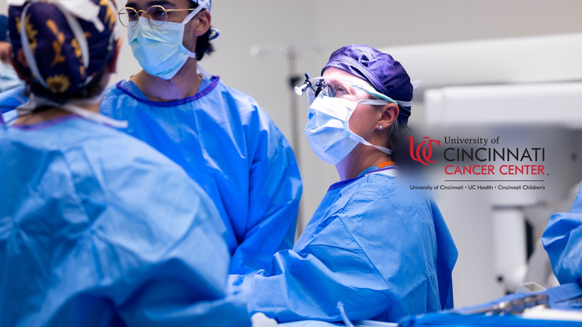 Physicians in scrubs and masks attend to a patient's medical procedure. 