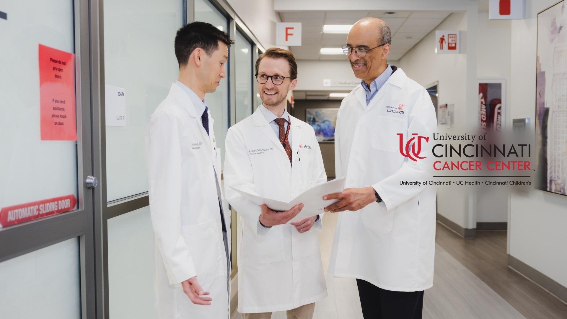 Three medical providers talk in a hallway. 