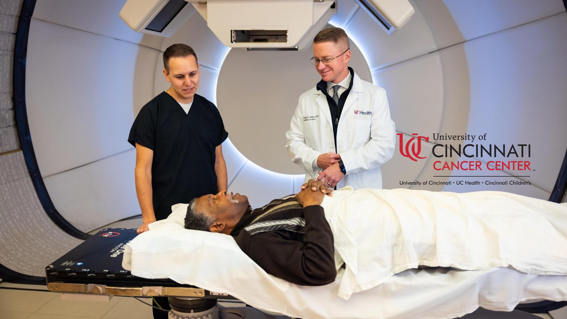 Medical providers talk with a patient in front of a proton beam therapy machine. 