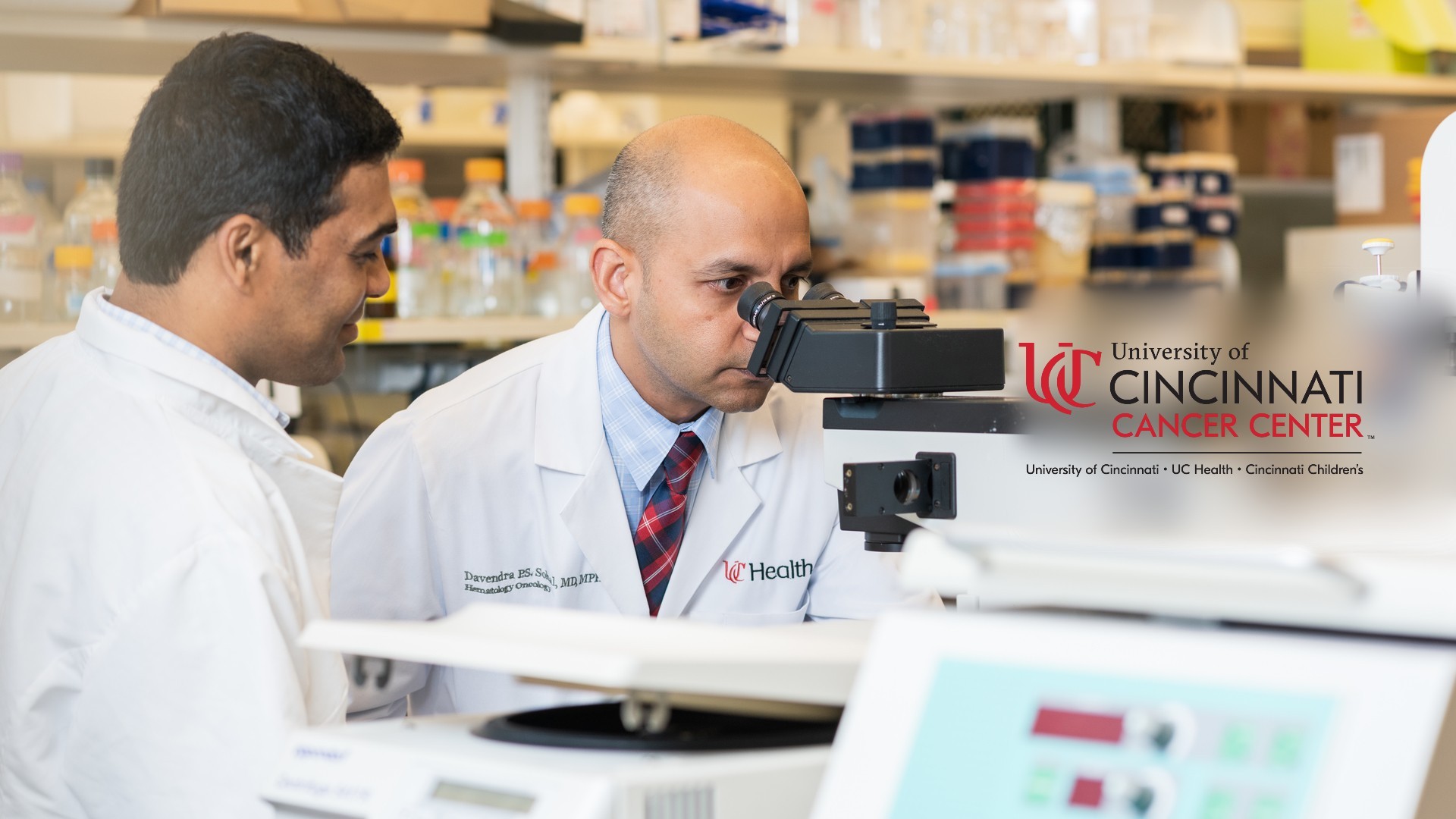 Medical providers work in a lab with a microscope. 