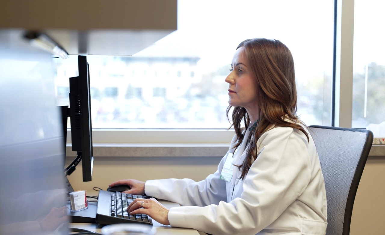 Physicians talk with a patient in an exam room. 