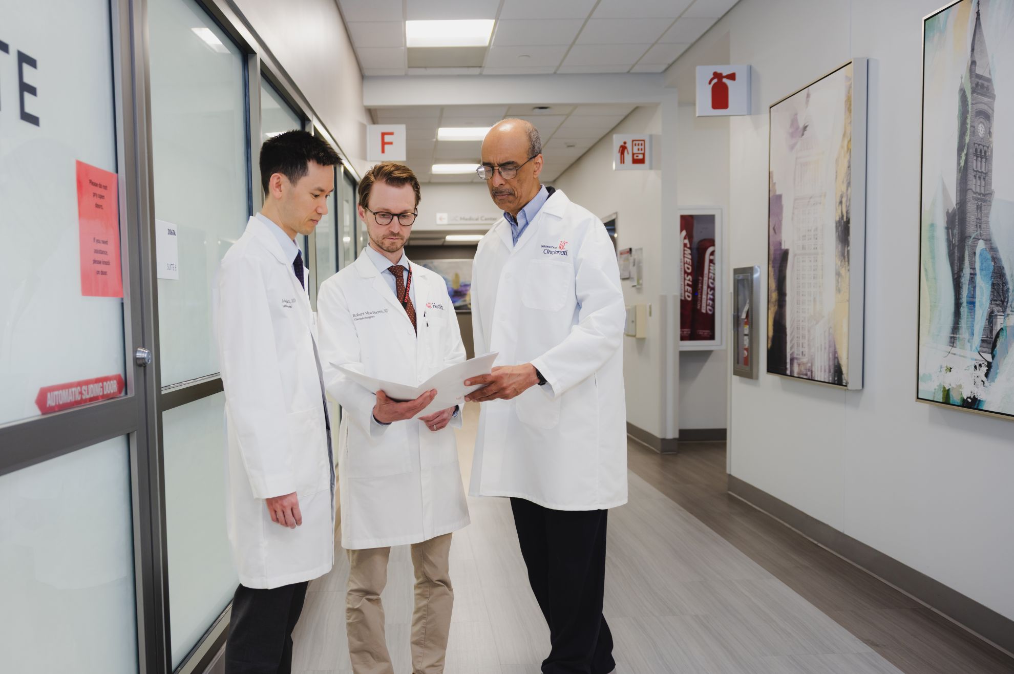 Physicians discuss paperwork in a hallway. 