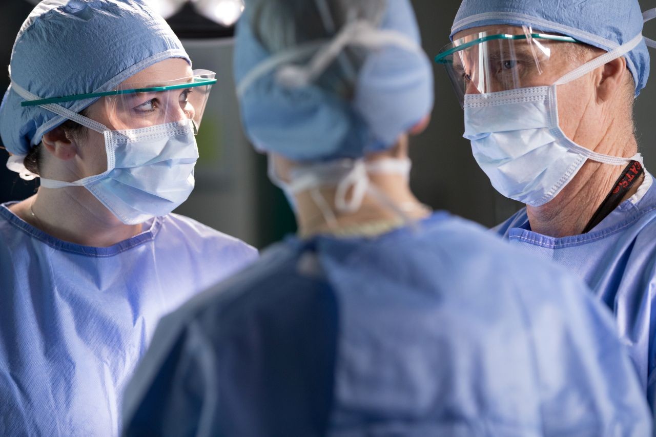 Physicians in masks and scrubs talk. 