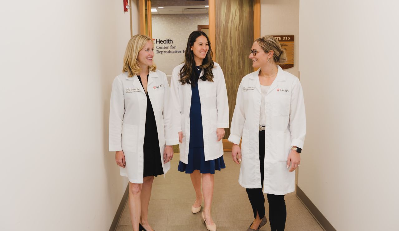 Three physicians walk through a hallway. 