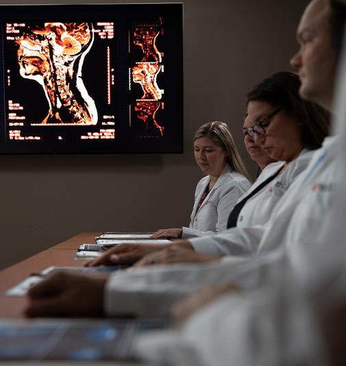 Panel of physicians review documents before them on a table.