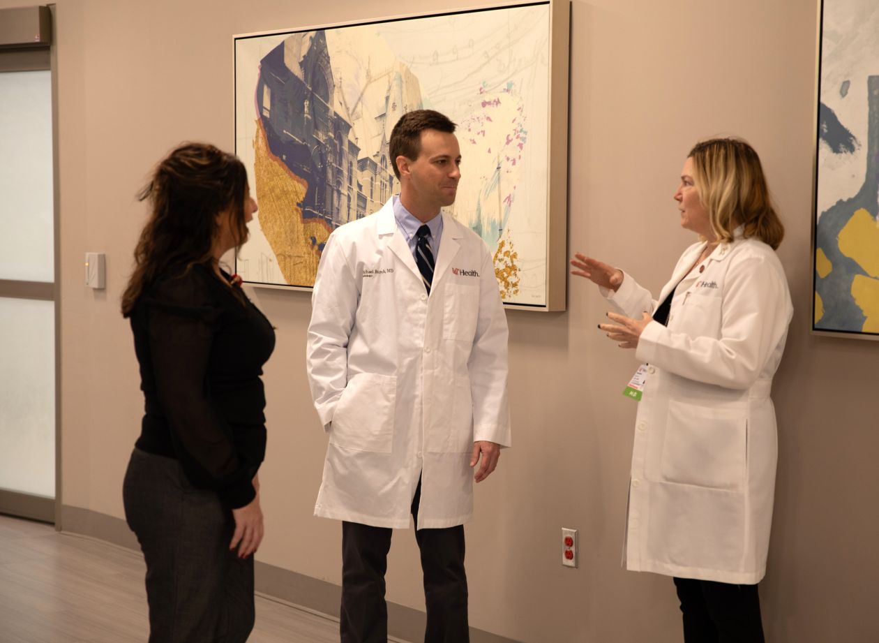Three physicians meet in a hallway and talk. 