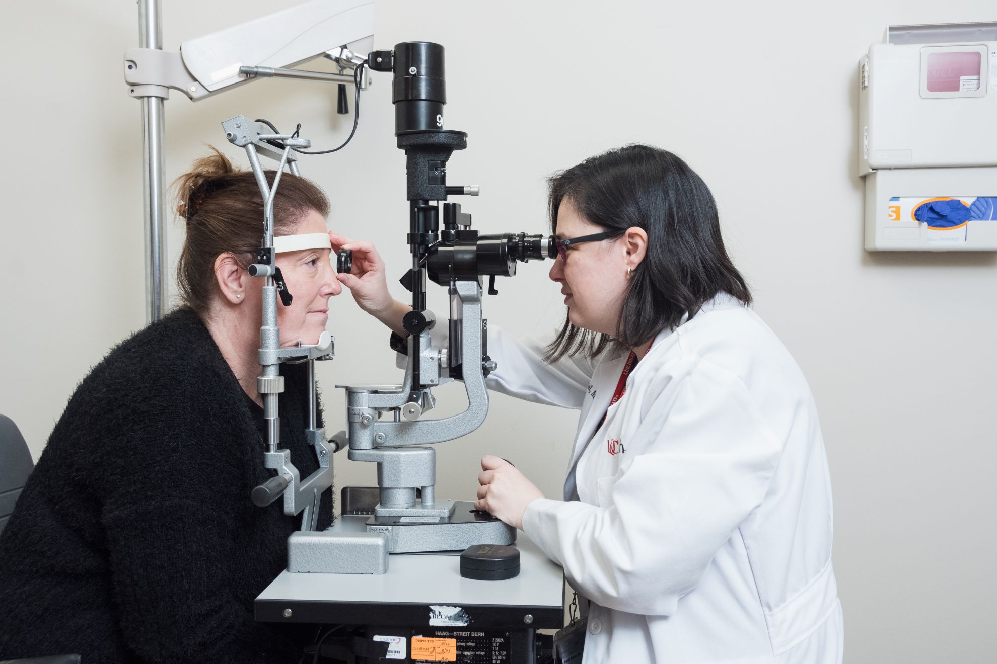 Physician looks through a medical device to examine patient's eyes.