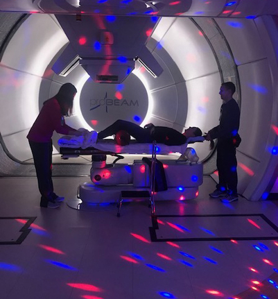 Three medical staff walk through a sunlit hallway. 