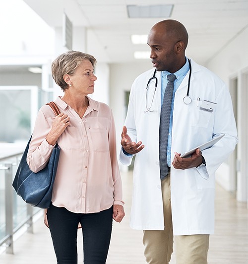 Physician walks with a patient in a hallway. 