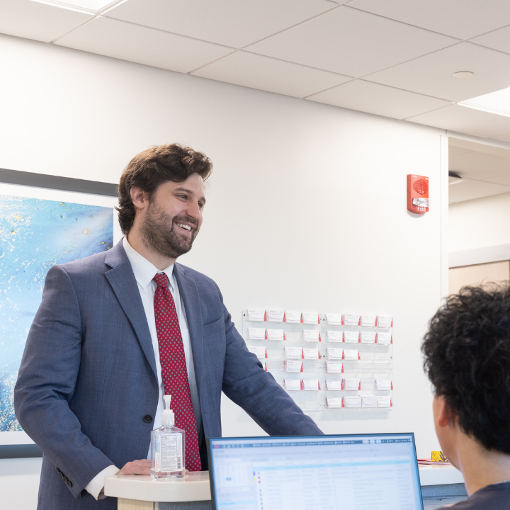 Medical personnel talks with a person at a table. 