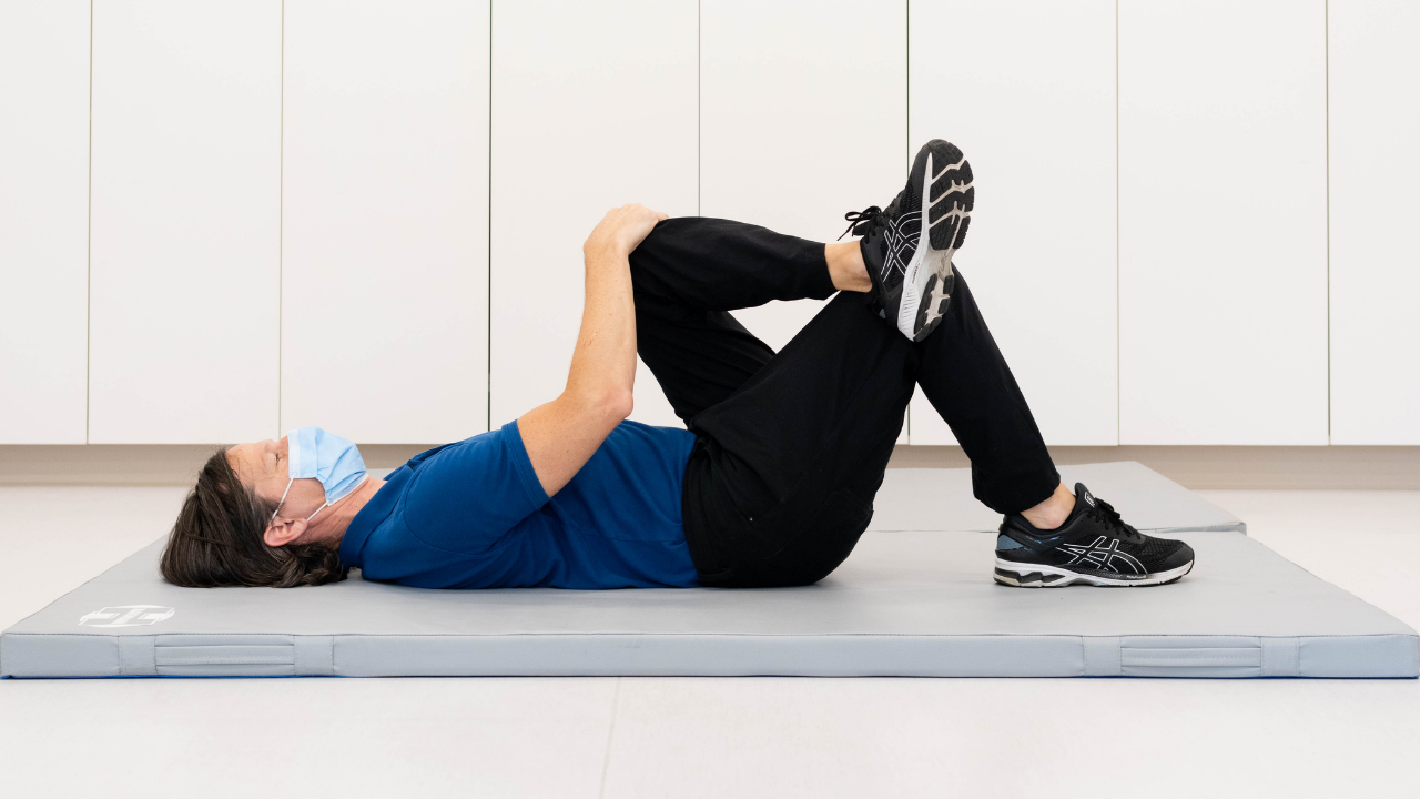 Physician attends to a patient while a person in the background looks on.