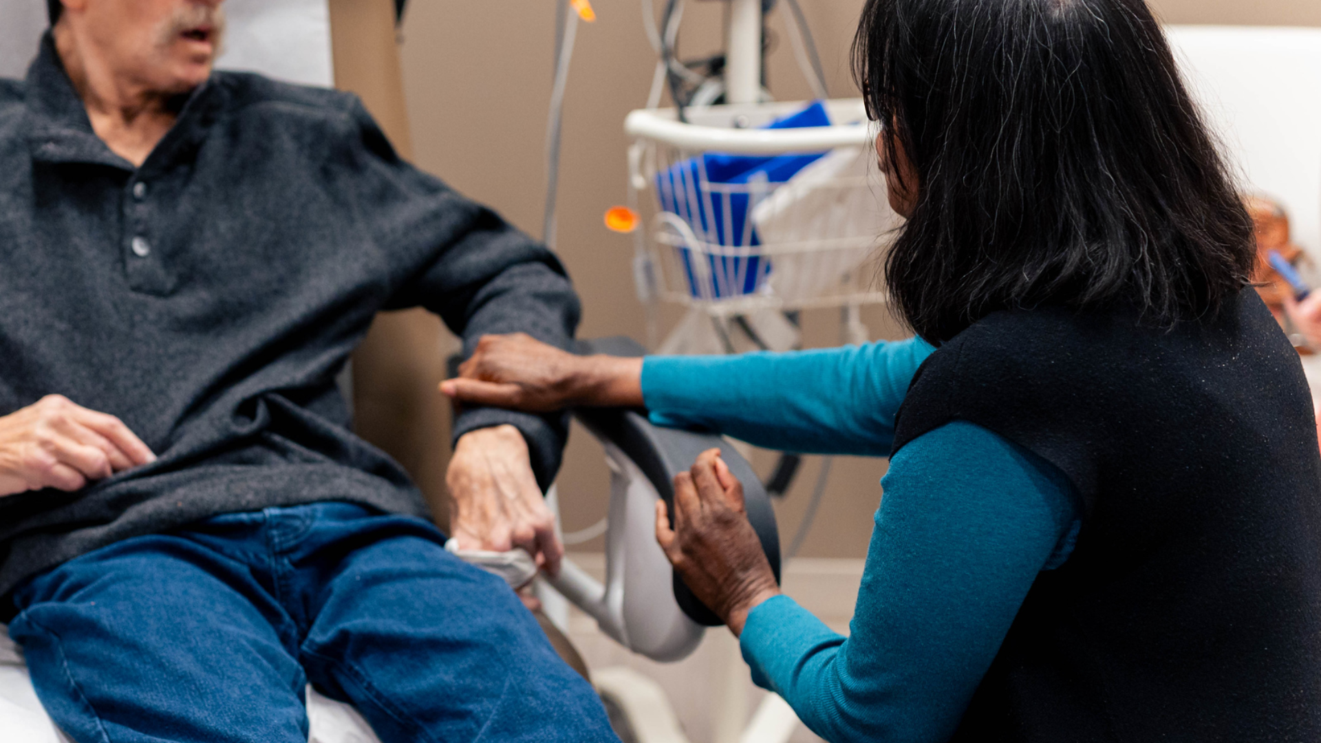 Patient holding hands with another person in a medical environment. 