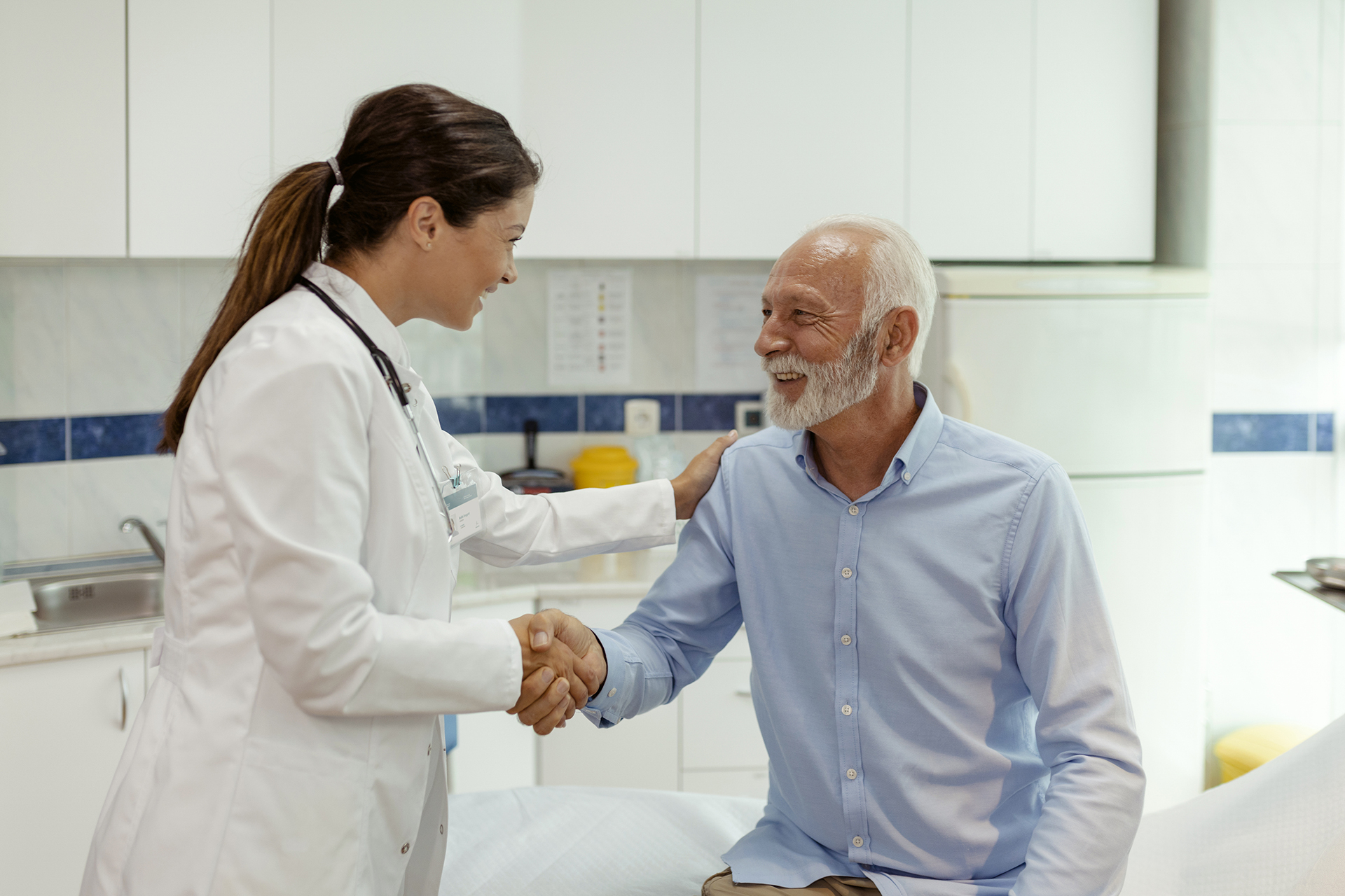 Doctor shaking hands and meeting patient in exam room.
