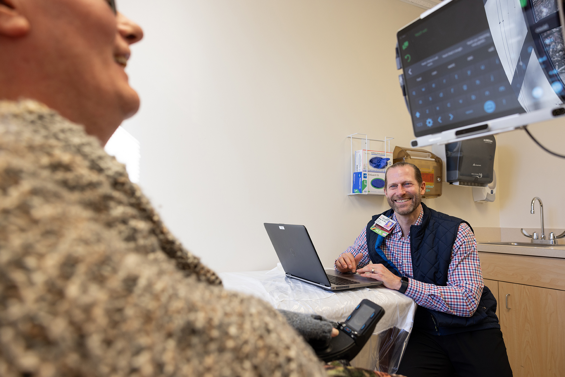 ALS doctor smiles with patient in exam room.