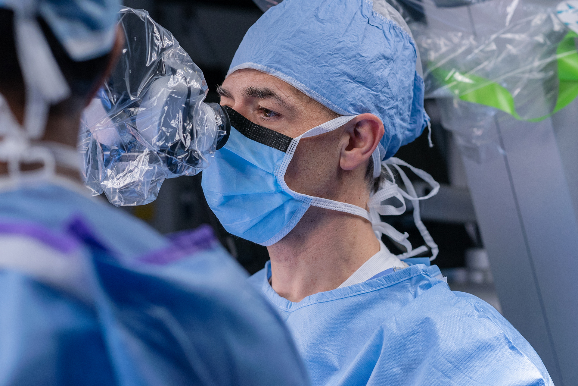 Physician looks through a device while performing a procedure.