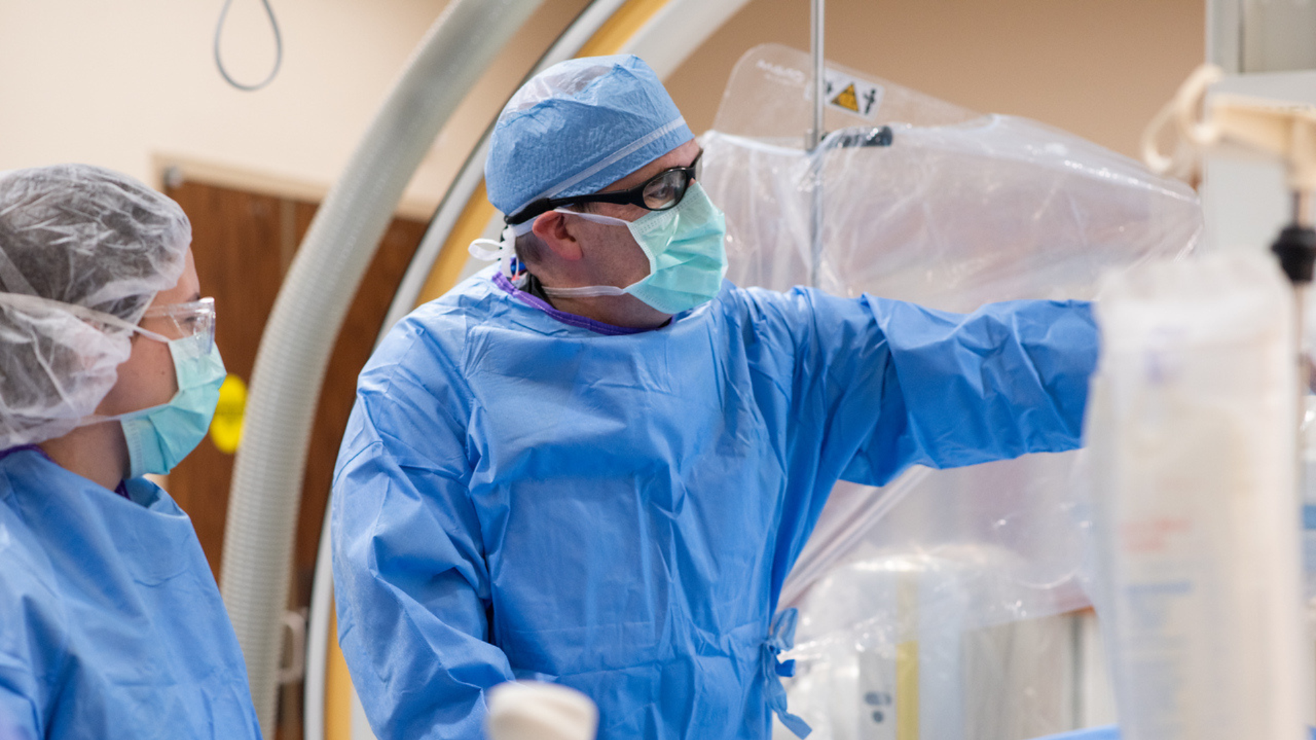 Physician in mask and scrubs performs a medical procedure. 