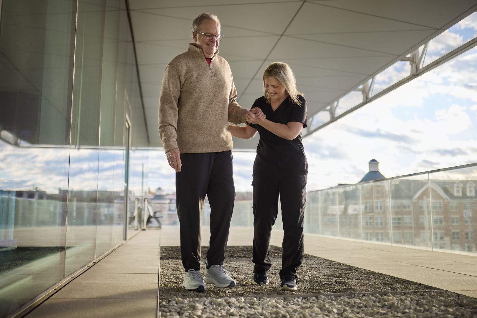 Physician helps patient walk across floor during therapy.
