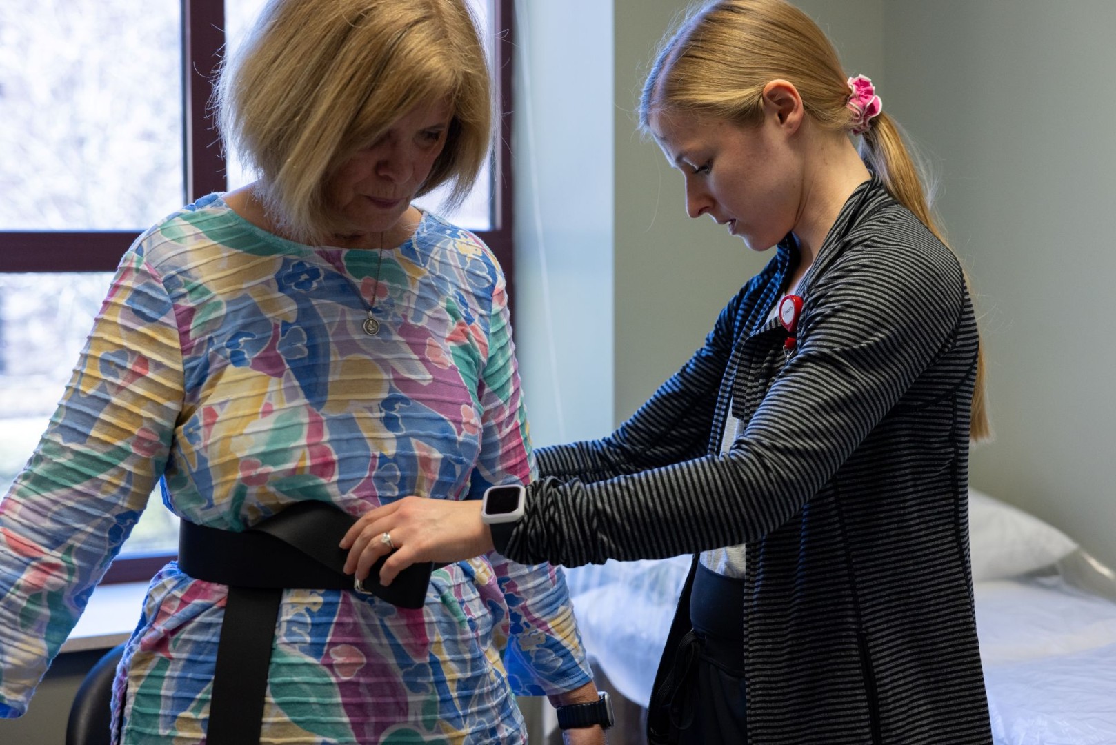 Meedical provider helps to fit a belt around a patient's waist. 