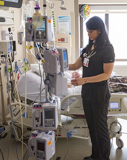 Nurse works on equipment in a medical room. 
