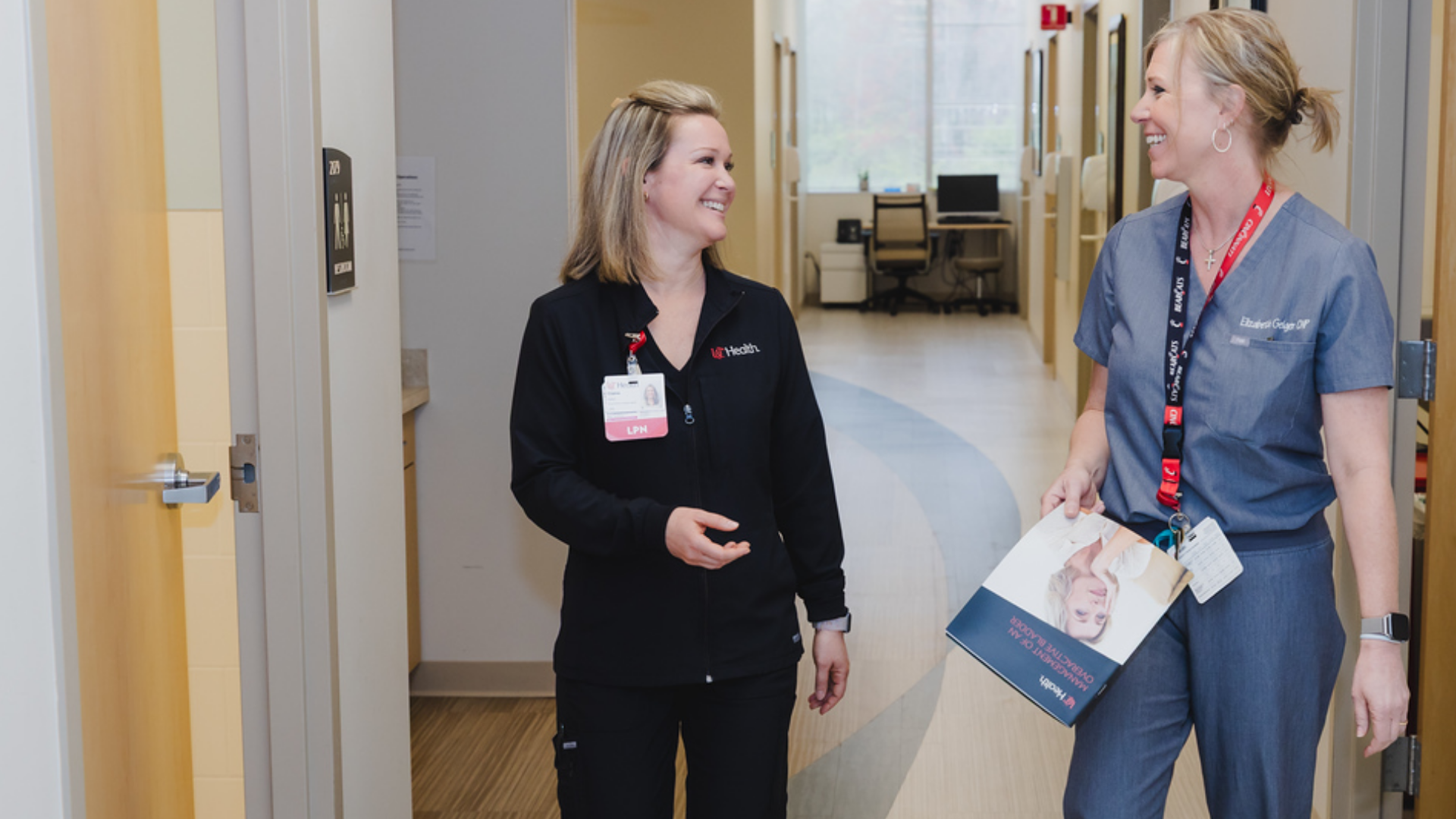 Physicians talk while walking in a hallway.