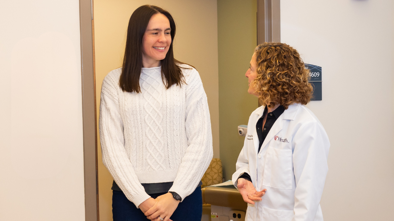 A physician talks with a patient in an exam room. 