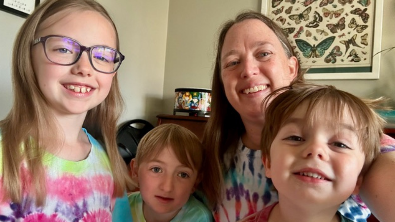 Kelly and her three children smile for the camera in their tie-dye t-shirts