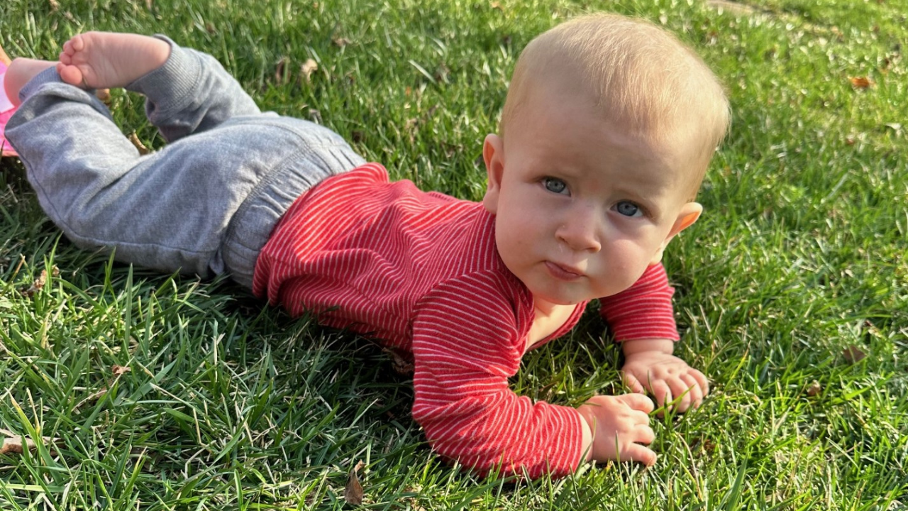Nicole's youngest child lays in the grass and looks at the camera.