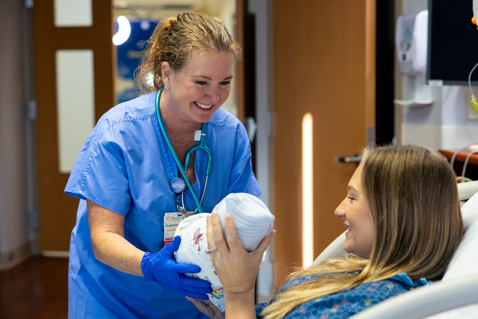 Nurse handing patient her new baby