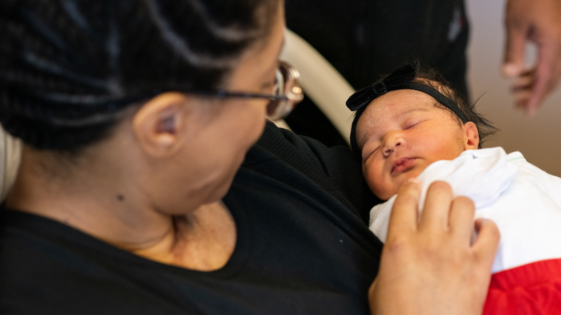 A mom looks at her sleeping newborn baby.