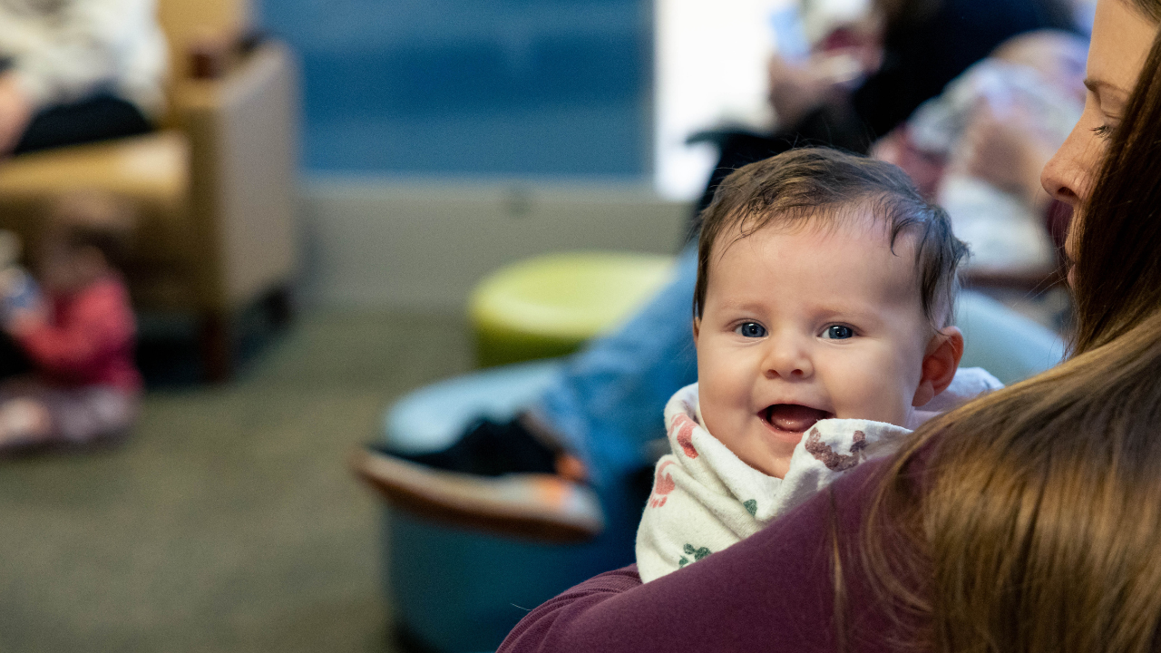 Baby smiles at the camera during UC Health's Baby Cafe 