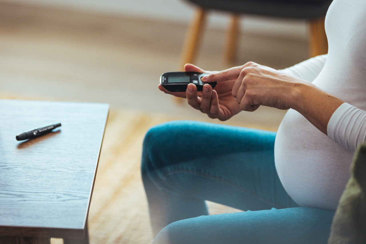 Pregnant women uses a diabetes monitor. 