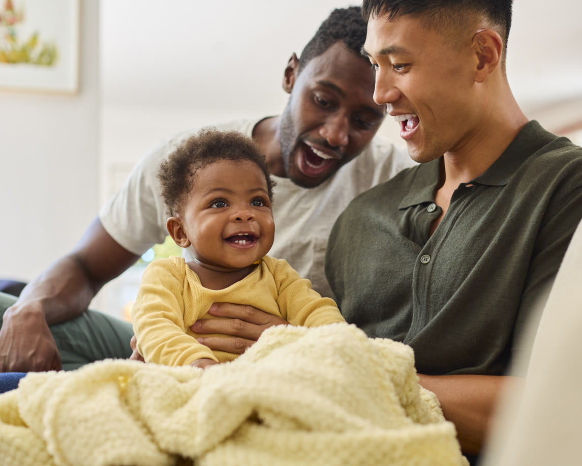 Two new fathers hold their young baby