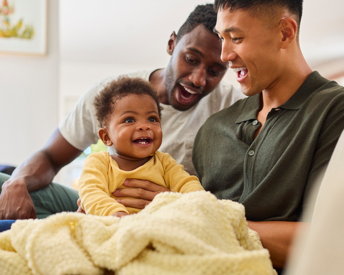 Two new fathers hold their young baby