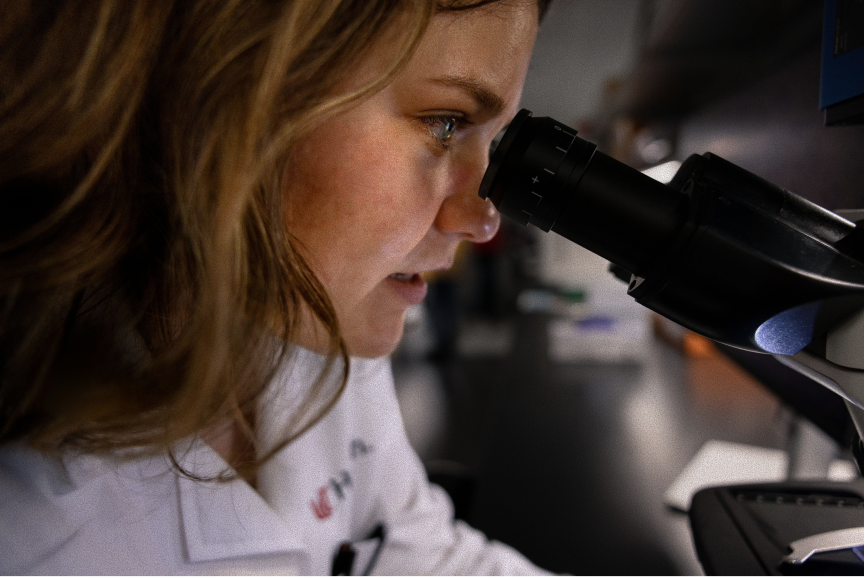 UC Health researcher looks through microscope.